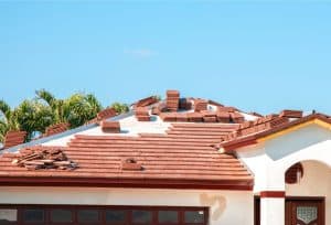 Red tile roof undergoing replacement with new roofing materials and stacked tiles on a residential home.